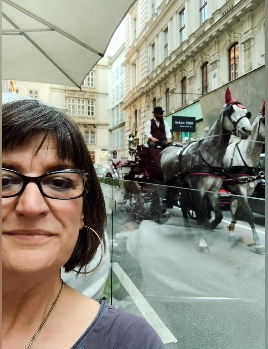 founder Barbara Anne Bauer at Café€e Dials, horse drawn carriage in background